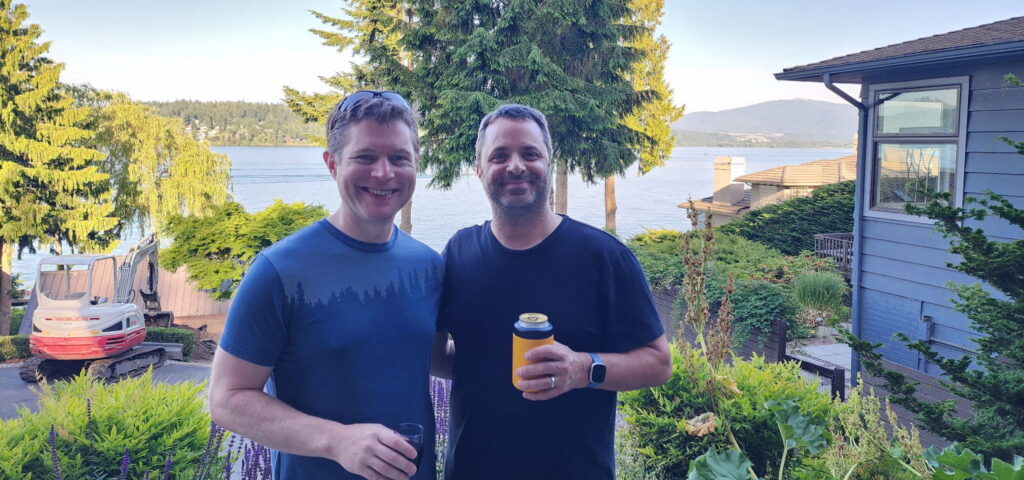 StatBid co-founders Shilo Jones and Roy, smiling outdoors with a lake and mountain view in the background