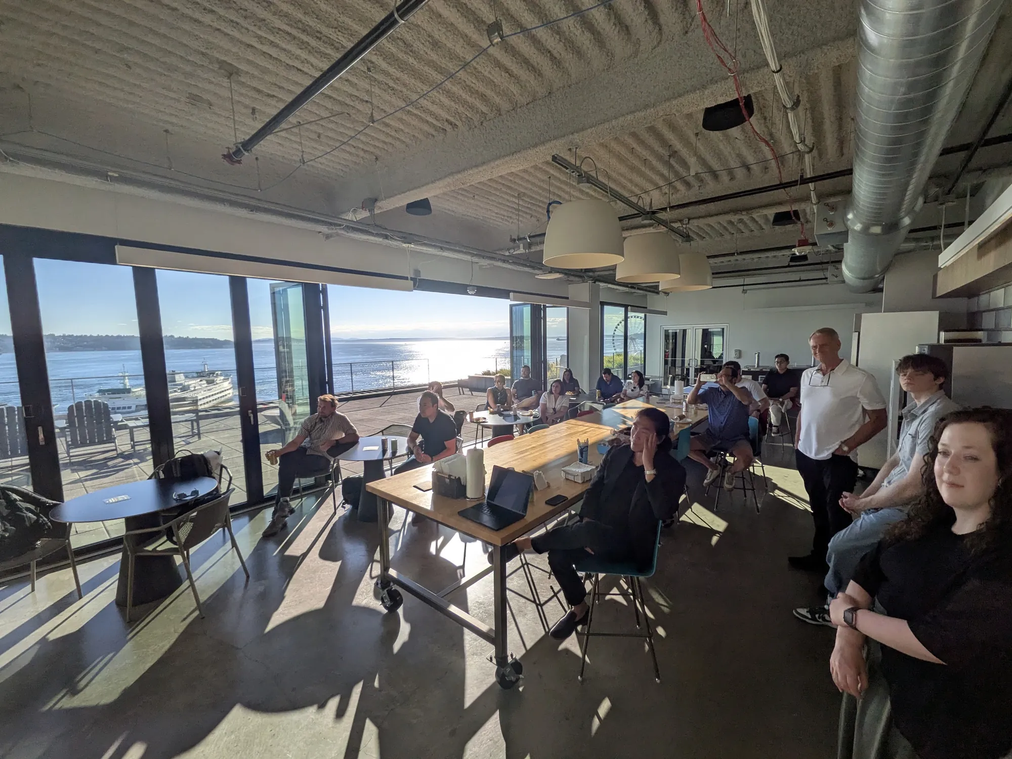 Attendees seated at long tables facing the windows over Elliott Bay