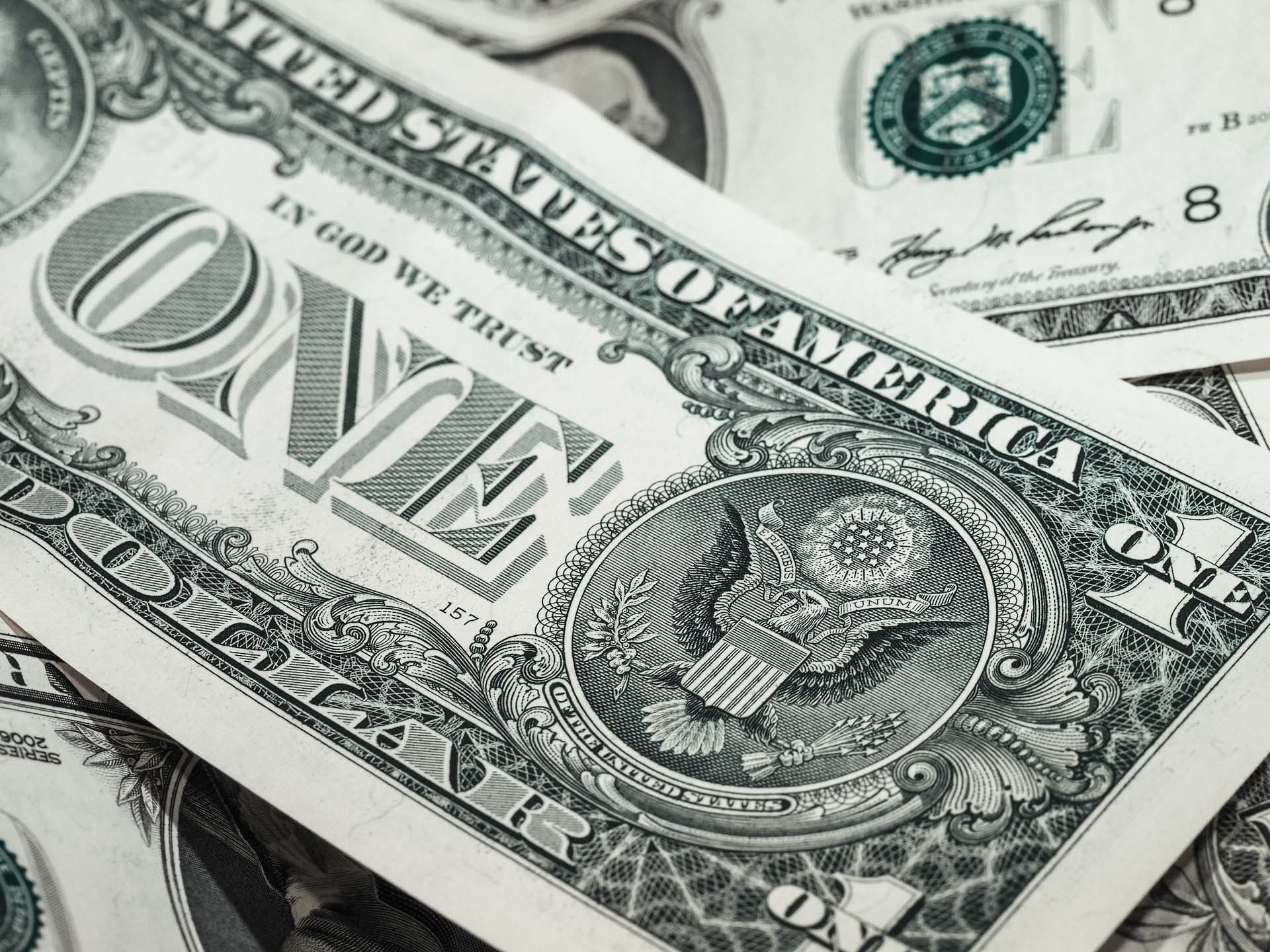 A close-up of overlapping US one-dollar bills, representing capital allocation and financial decision-making in a business context.