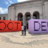 StatBid team members standing between the giant DOT and DEV letter sculptures outside Shopify dot dev