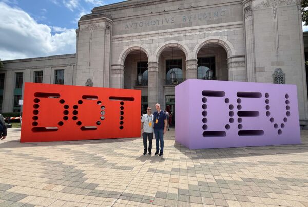 StatBid team members standing between the giant DOT and DEV letter sculptures outside Shopify dot dev
