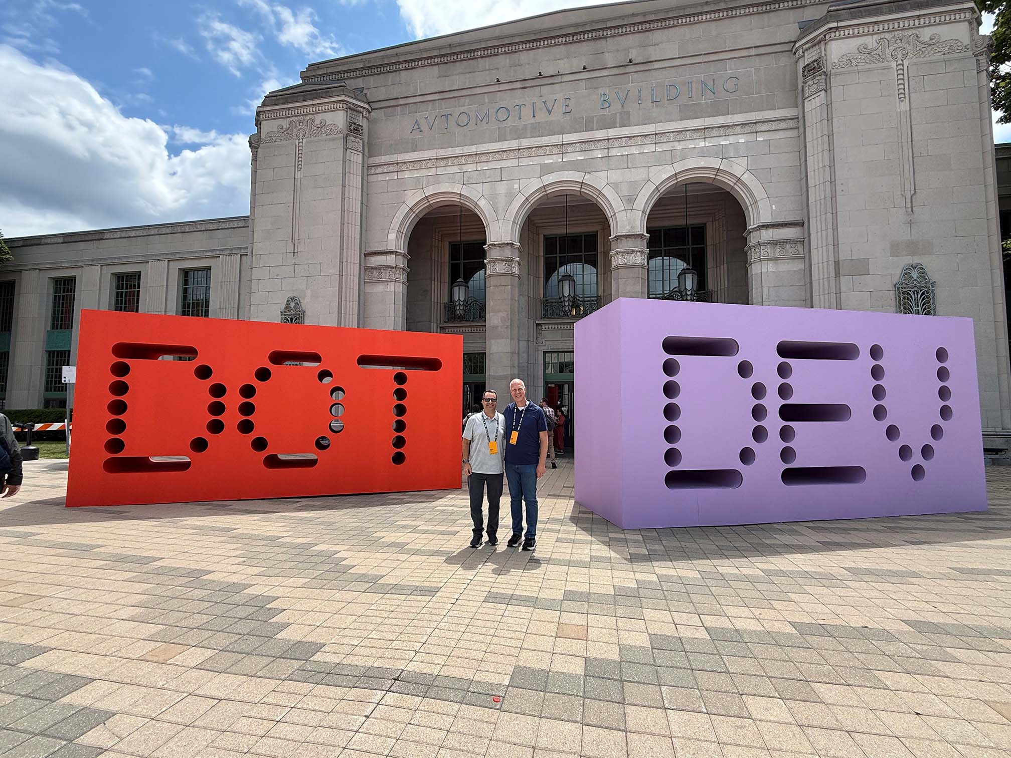 StatBid team members standing between the giant DOT and DEV letter sculptures outside Shopify dot dev